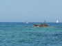 Gita in barca a Baratti, Piombino (LI) - Un gommone ed una barca a vela fanno da sfondo allo Scoglio dello Stellino. La croce  stata posta in memoria di un sub della zona ufficialmente disperso in mare dal 1989. La stampa locale, alcuni testimoni ed alcune prove dimostrerebbero l
