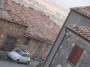 Montemassi, Roccastrada (GR) - Un gatto ed una vecchia Fiat 500 con lo sfondo delle case del paese con antichi tetti a tegole, porte con trave in legno e della campagna maremmana - Fotografia 8 dicembre 2011, Toscana