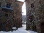 Montieri (GR) - Antichi edifici con pareti a sasso in vista nel centro storico del paese. In alto si nota un caratteristico lampione. Sullo sfondo il candore della neve fra la vegetazione - Fotografia Marzo 2010