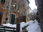 Montieri (GR) - La panchina in fondo alla salita di via della Ruga  coperta da un mucchi di neve. Lungo la strada lastricata in pietra si affacciano antichi edifici con le facciate a sasso a vista, caratteristici balconi e lampioni - Fotografia Marzo 2010