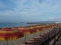 Spiaggia di Carbonifera, Piombino (LI) - Ombrelloni e sdraio di un bagno della spiaggia. La vista  rivolta verso nord. Sullo sfondo oltre il pontile si scorge il promontorio di Piombino, mentre sulla sinistra si riconosce il profilo dell